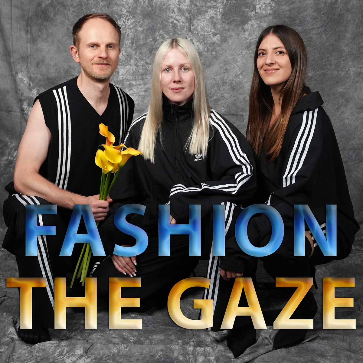 Das Bild zeigt die Podcaster von "Fashion The Gaze". Die drei Personen sind vor einem grauen Hintergrund zu sehen und tragen alle schwarze Trainingsanzüge mit weißen Streifen. Links sitzt ein Mann mit kurzem Haar, der einen ärmellosen Trainingsanzug trägt und einen Strauß gelber Calla-Lilien in der Hand hält. In der Mitte sitzt eine Frau mit langen, blonden Haaren, die einen Trainingsanzug mit Reißverschluss trägt. Rechts sitzt eine Frau mit langen, braunen Haaren, die ebenfalls einen Trainingsanzug trägt und lächelt. Der Text "FASHION THE GAZE" ist in großen, blau-gelben Buchstaben über das Bild gelegt.